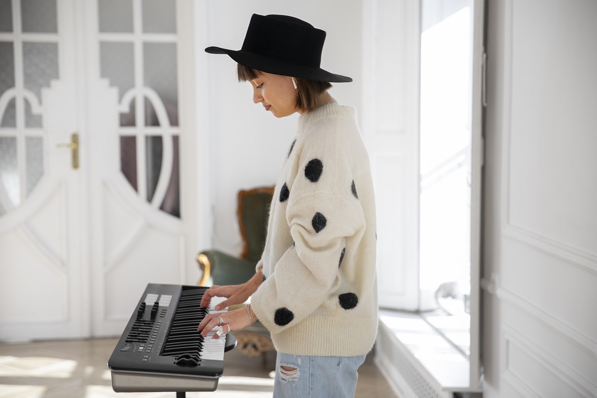 Jovem tocando teclado musical dentro de casa